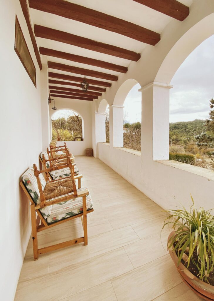 Wooden armchairs on a terrace with a serene forest view, highlighting rustic elegance.